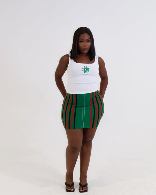 Woman wearing a white tank top with a logo and a green and red striped skirt on a white background